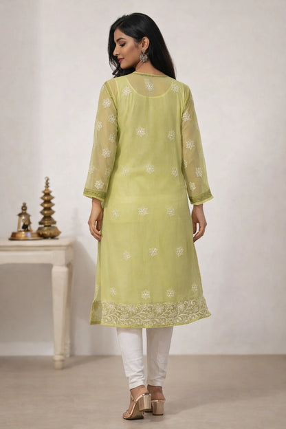 Woman wearing a light green kurta with white embroidery in a minimal setting.