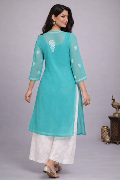 Woman wearing a turquoise kurta with white pants on a gray background