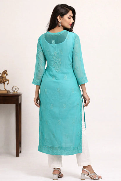 Woman wearing a turquoise kurta with white pants on a plain background