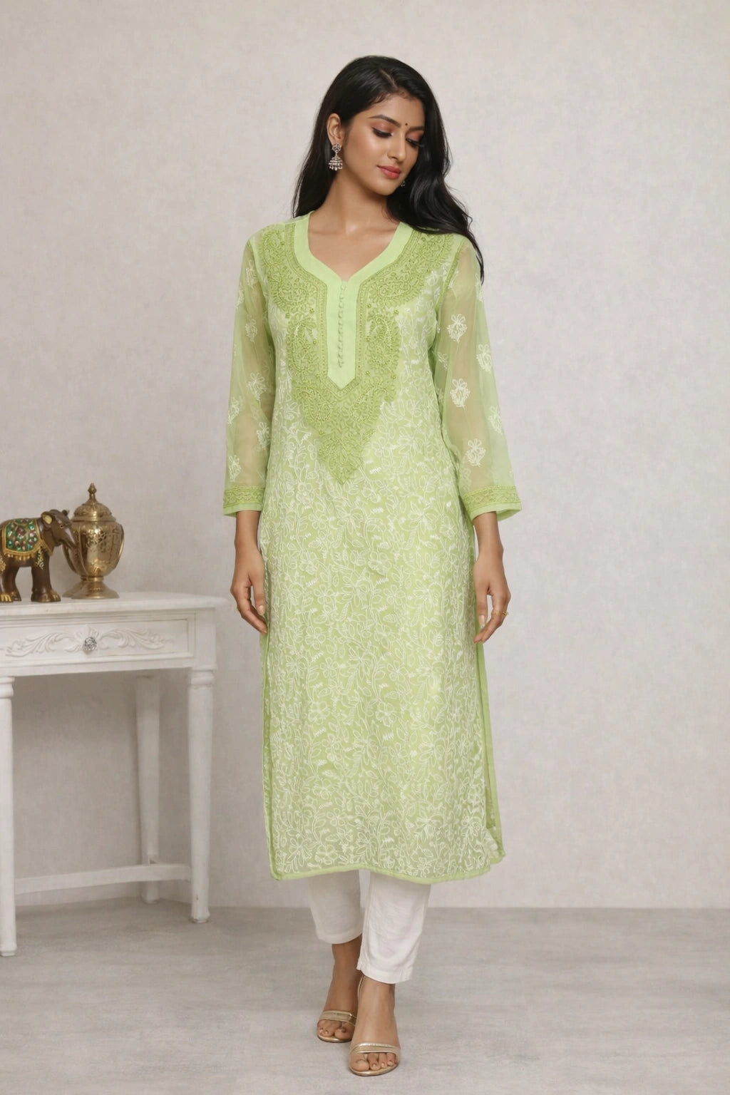 Woman wearing a light green embroidered kurta with white pants in a minimalistic setting.
