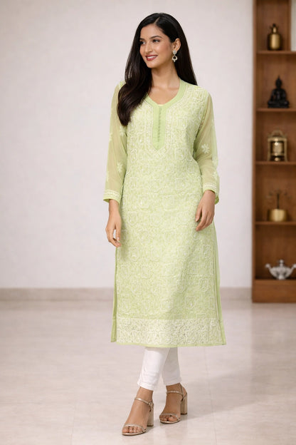 Woman wearing a light green embroidered kurta with white pants in a minimalistic setting.