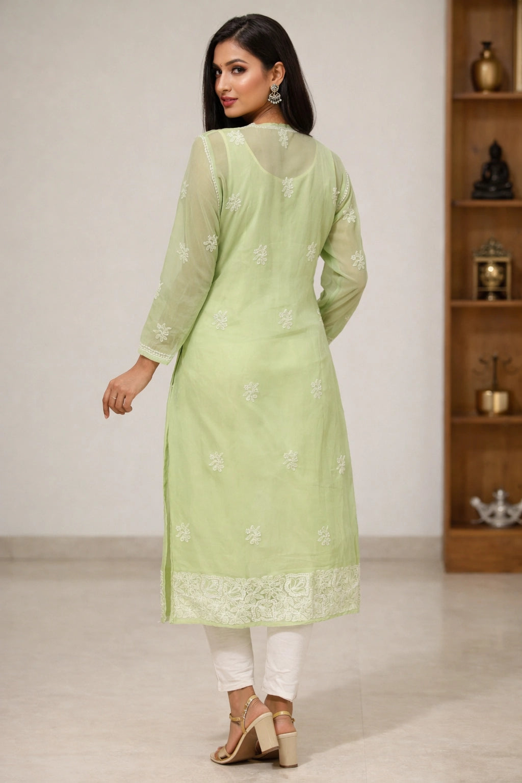 Woman wearing a light green kurta with white embroidery in a minimal indoor setting.