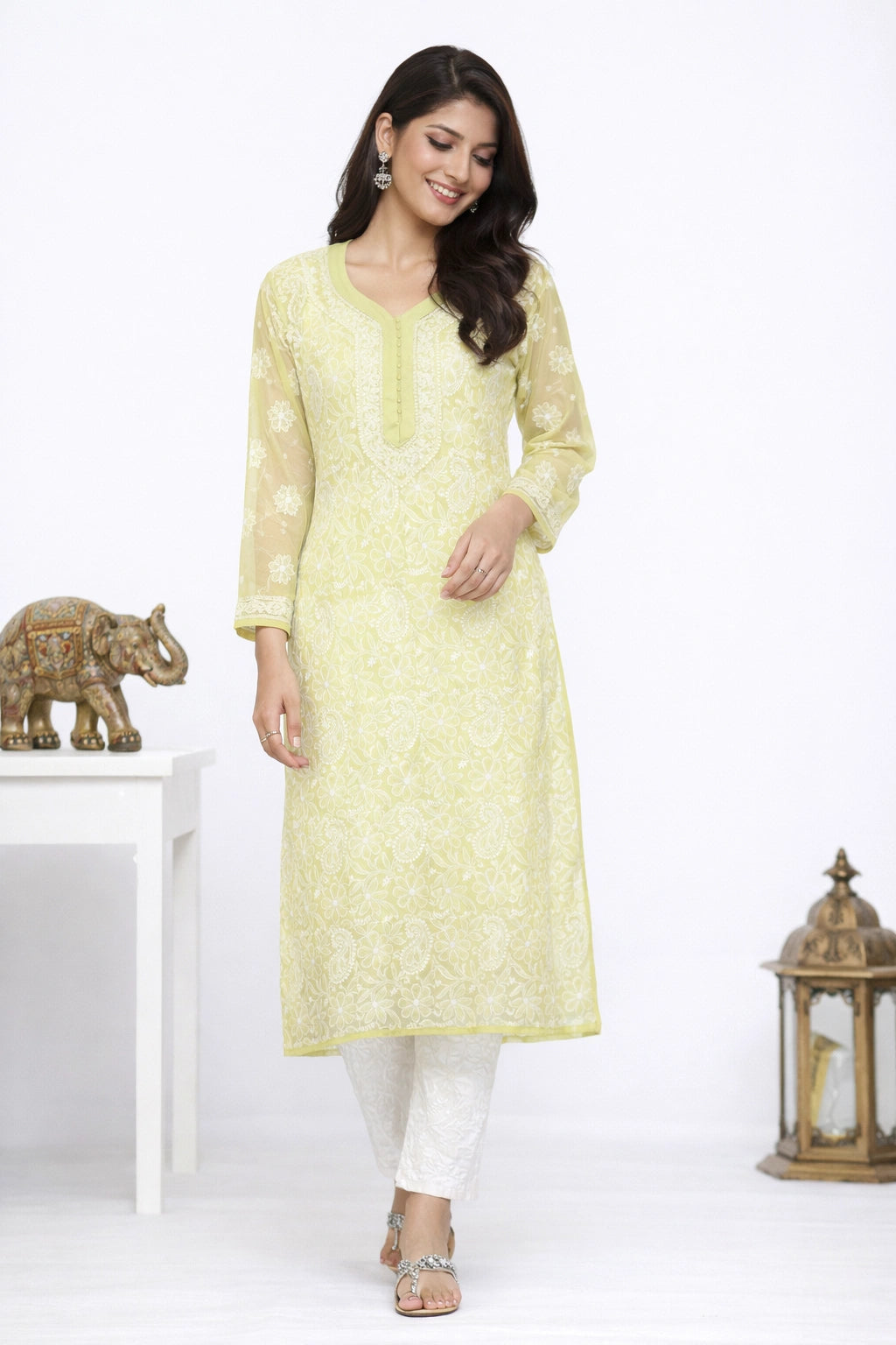 Woman wearing a light yellow kurta with white pants in a minimalistic setting.