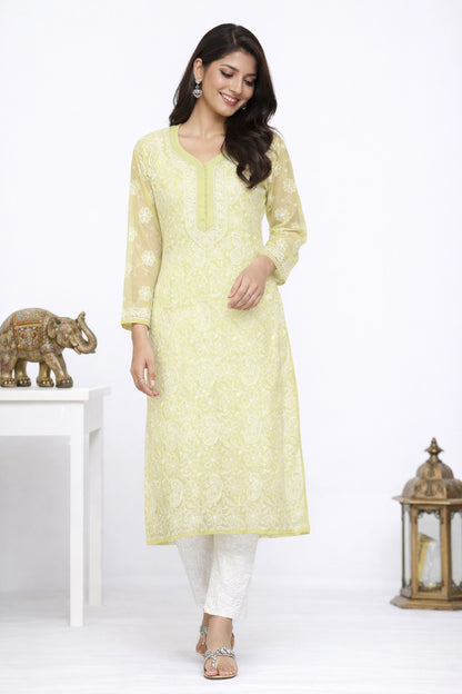 Woman wearing a light yellow kurta with white pants in a minimalistic setting.