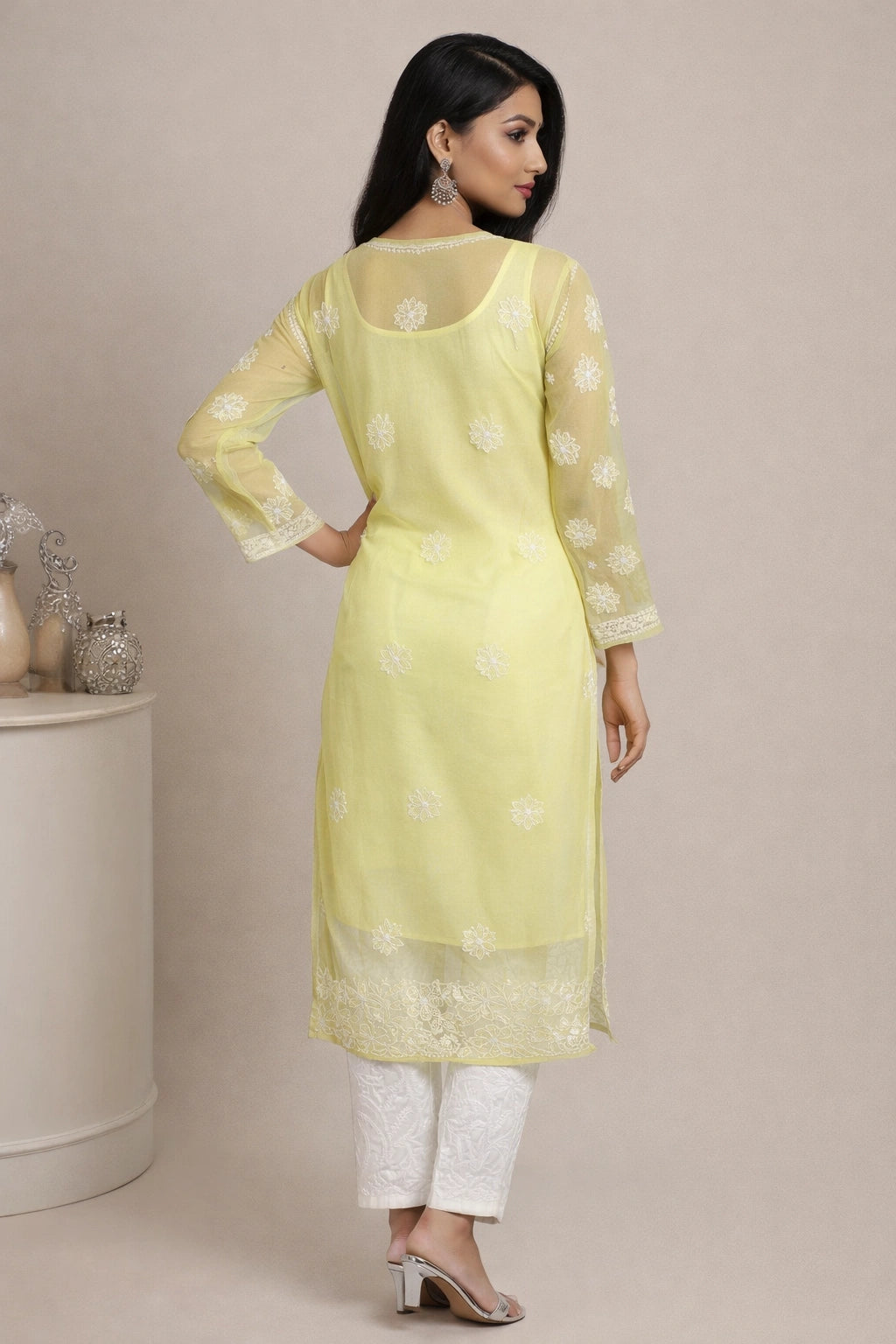 Woman wearing a light yellow kurta with white patterns on a beige background