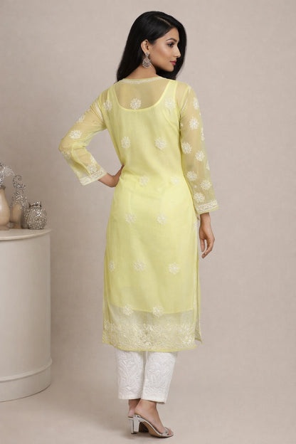 Woman wearing a light yellow kurta with white patterns on a beige background