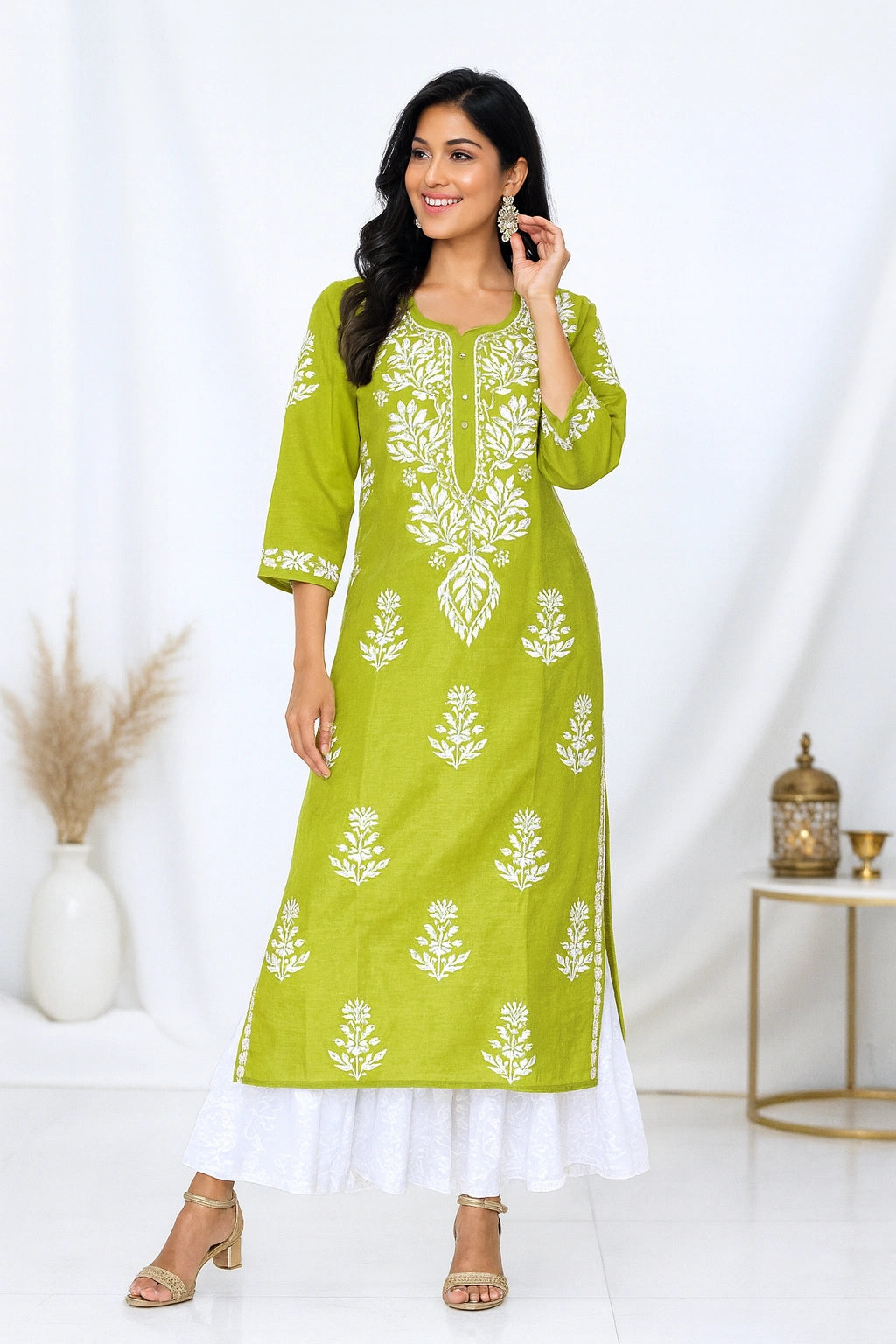 Woman wearing a green embroidered kurta with white pants on a white background