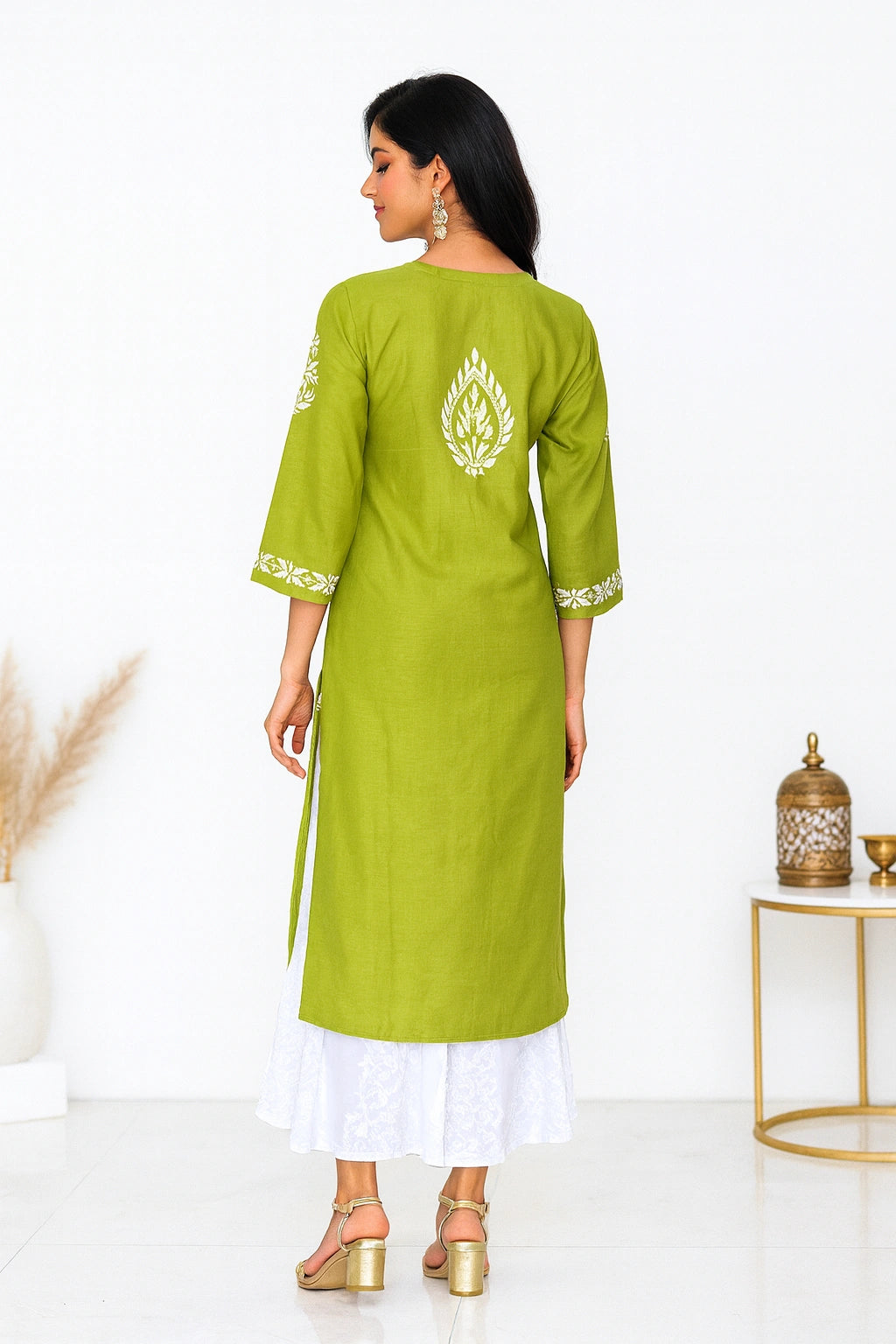 Woman wearing a green kurta with white embroidery in a minimalistic setting.