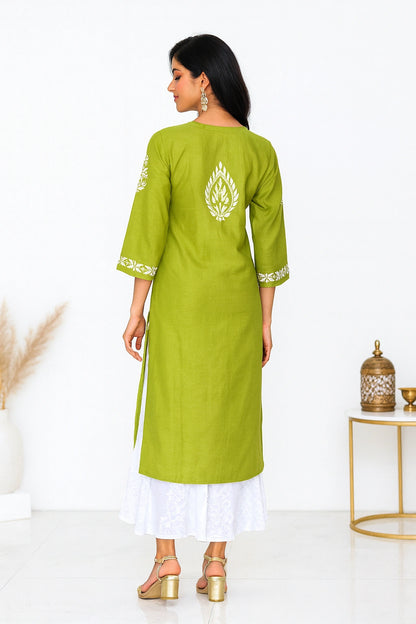 Woman wearing a green kurta with white embroidery in a minimalistic setting.