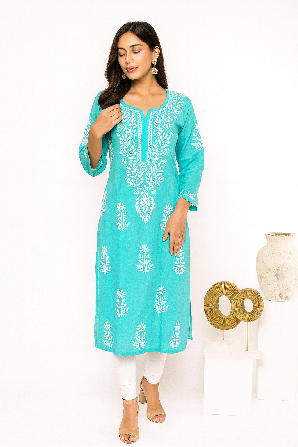 Woman wearing a green embroidered kurta with white pants on a white background
