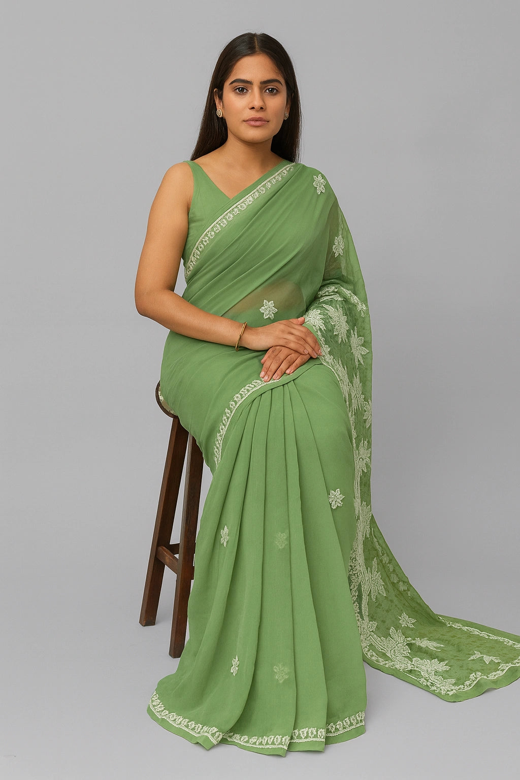 Woman wearing a green saree with white embroidery on a gray background