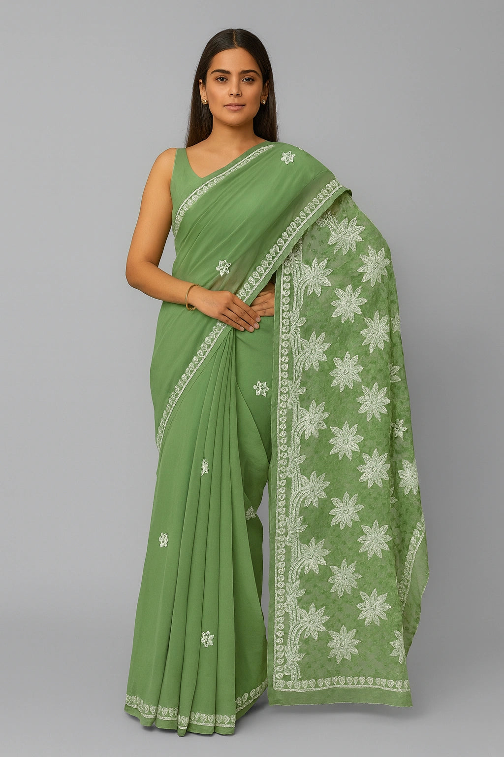 Woman wearing a lucknowi chikankari  green saree with white floral patterns on a gray background