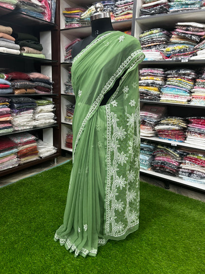 Green saree with white embroidery on a mannequin in a fabric store.