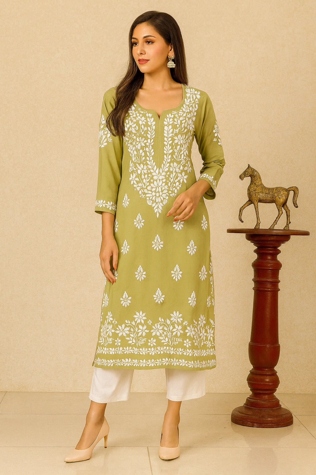 Woman wearing a green embroidered kurta with white pants in a minimalistic setting.