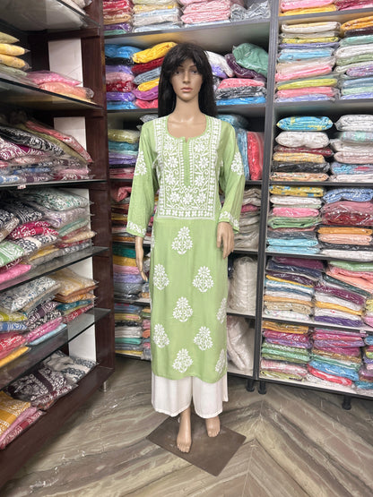 Mannequin wearing a green and white embroidered dress in a fabric store.