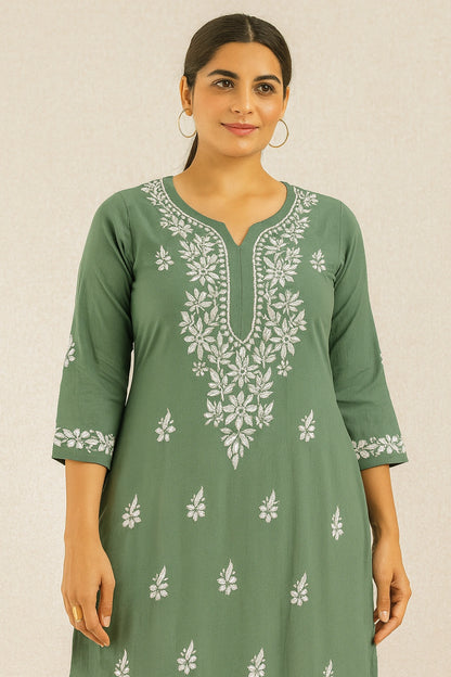 Woman wearing a green embroidered dress against a beige background