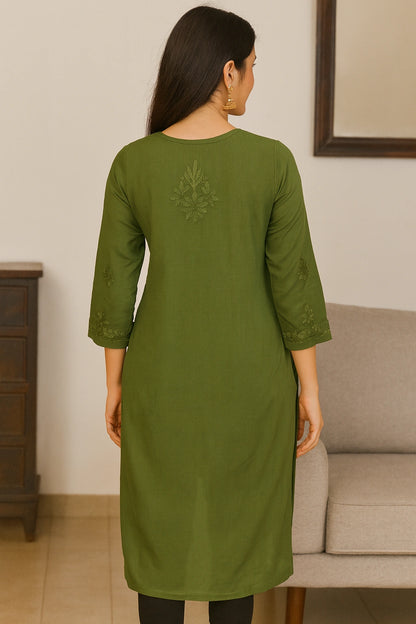 Woman wearing a lucknowi chikankari green kurta standing in a room with a neutral background