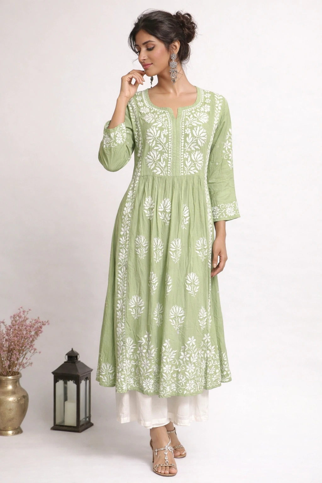 Woman wearing a green embroidered kurta with white patterns on a beige background