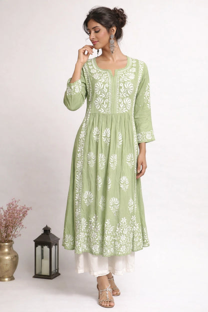 Woman wearing a green embroidered kurta with white patterns on a beige background