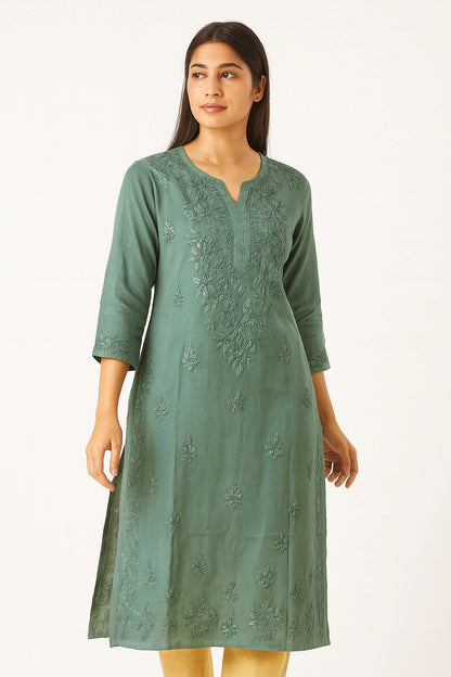 Woman wearing a green embroidered dress on a white background