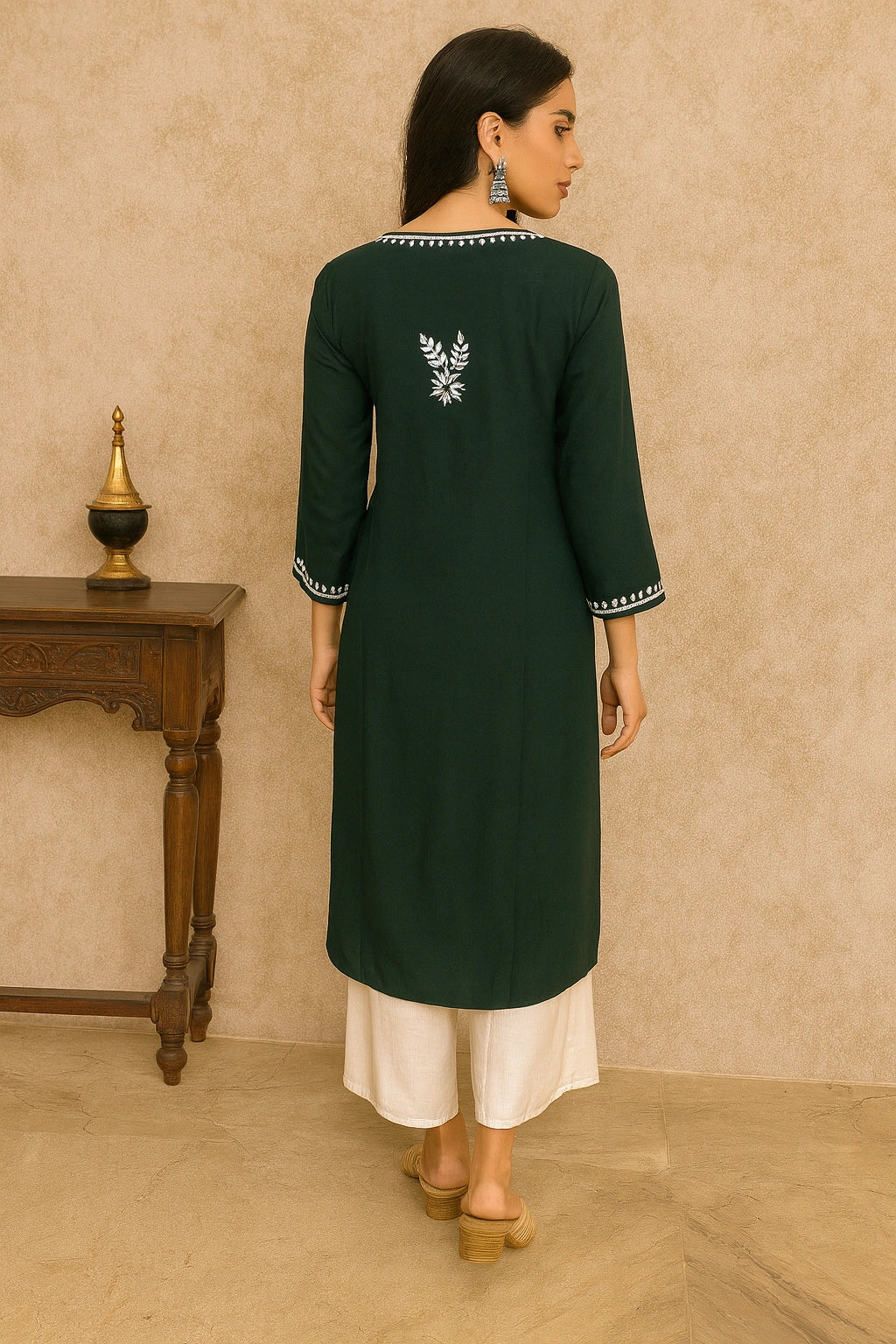 Woman wearing a green kurta with white embroidery in a minimalistic setting.