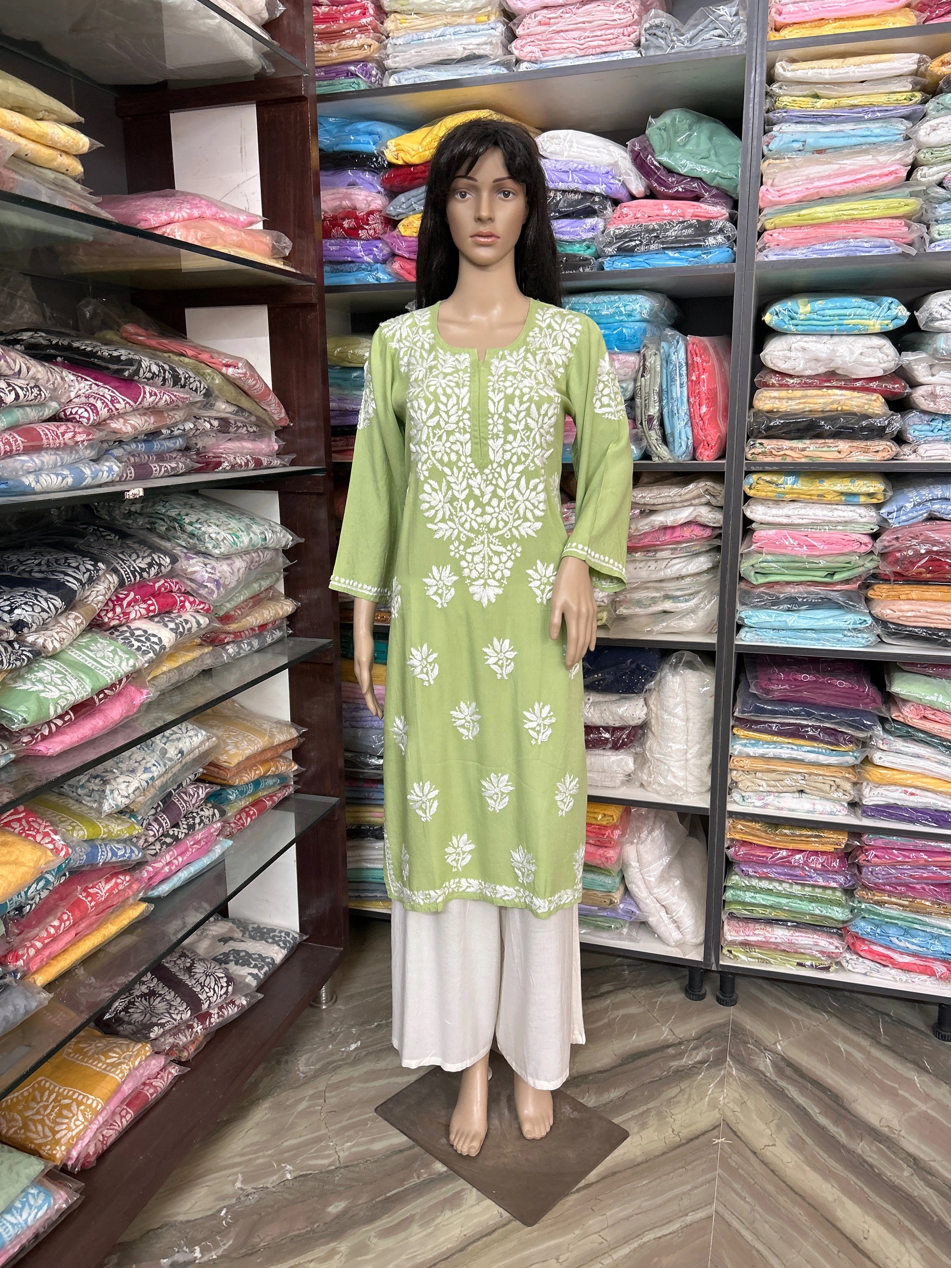 Mannequin wearing a green and white embroidered kurta in a fabric store.