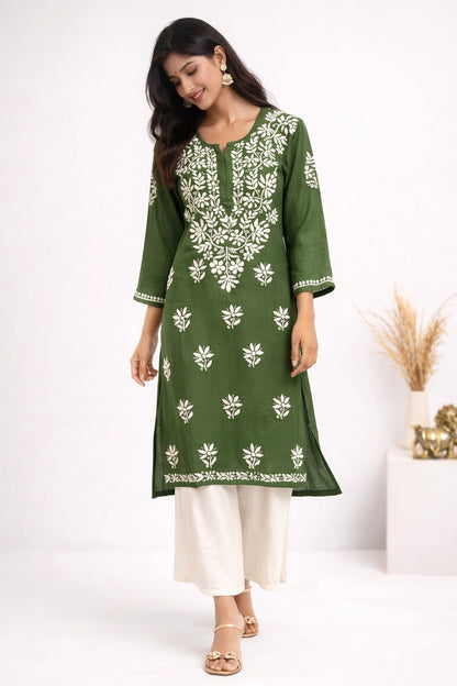 Woman wearing a green and white embroidered kurta with white pants on a white background