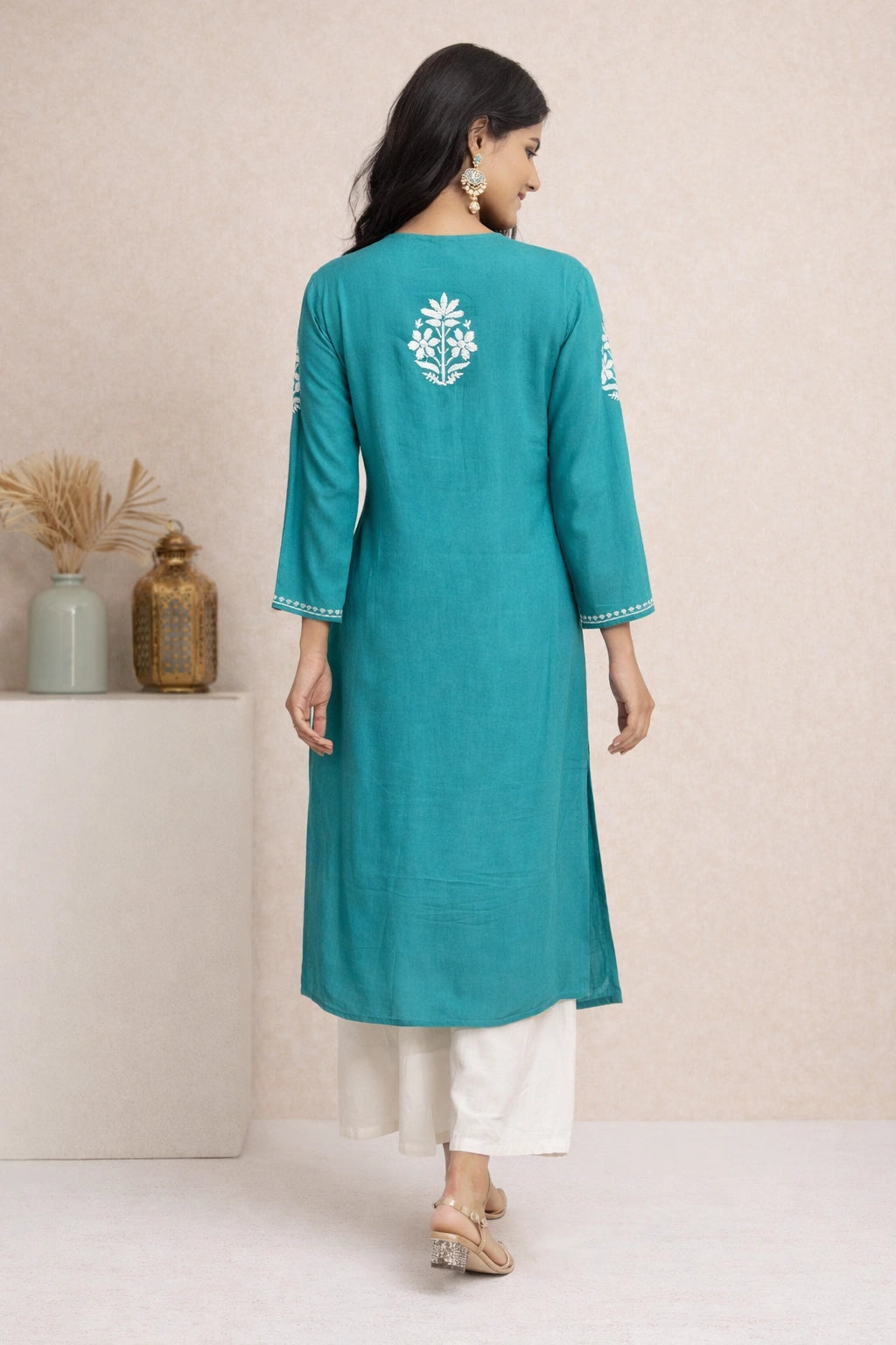 Woman wearing a teal kurta with white embroidery on a neutral background