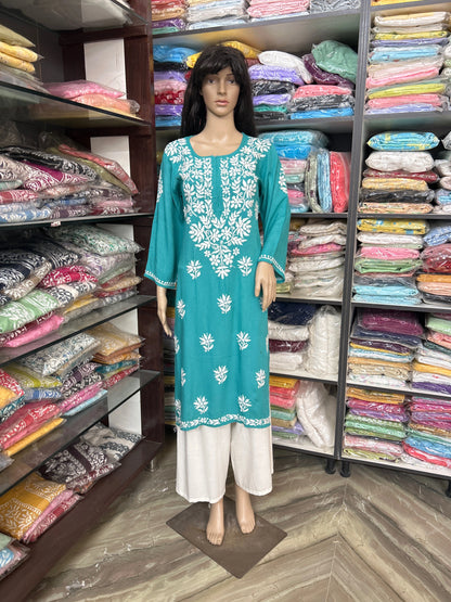 lucknowi chikankari Mannequin wearing a teal dress with white floral patterns in a fabric store.