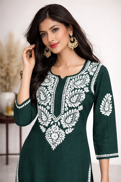 Woman wearing a green and white embroidered dress indoors.