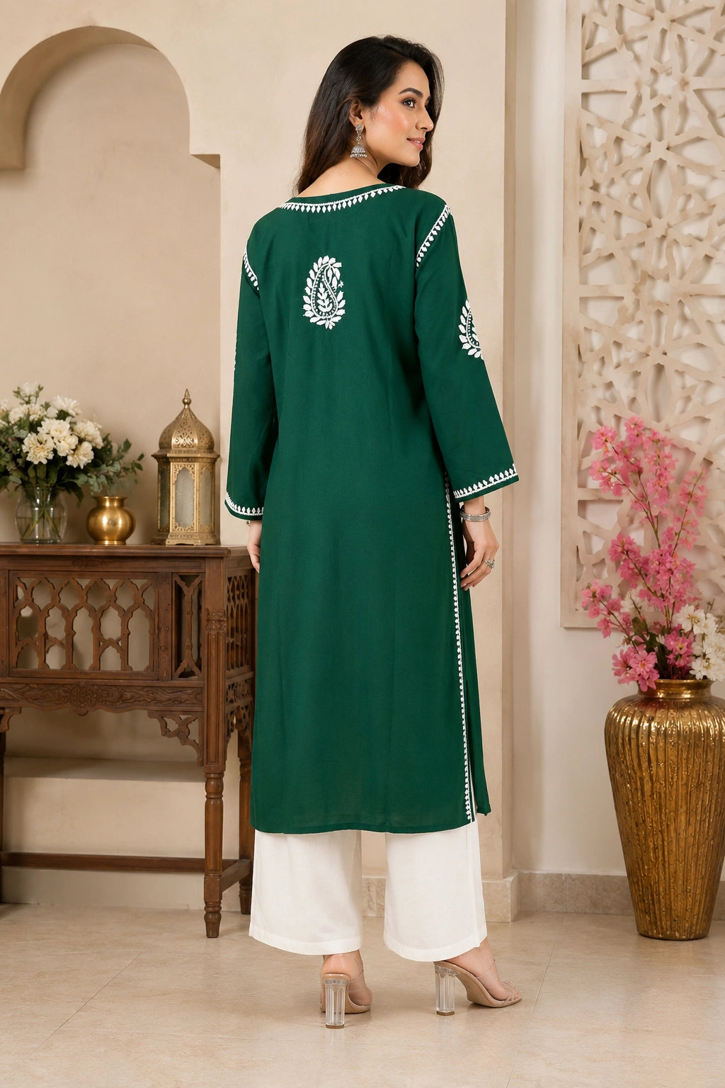 Woman wearing a green embroidered kurta with white pants in an indoor setting.