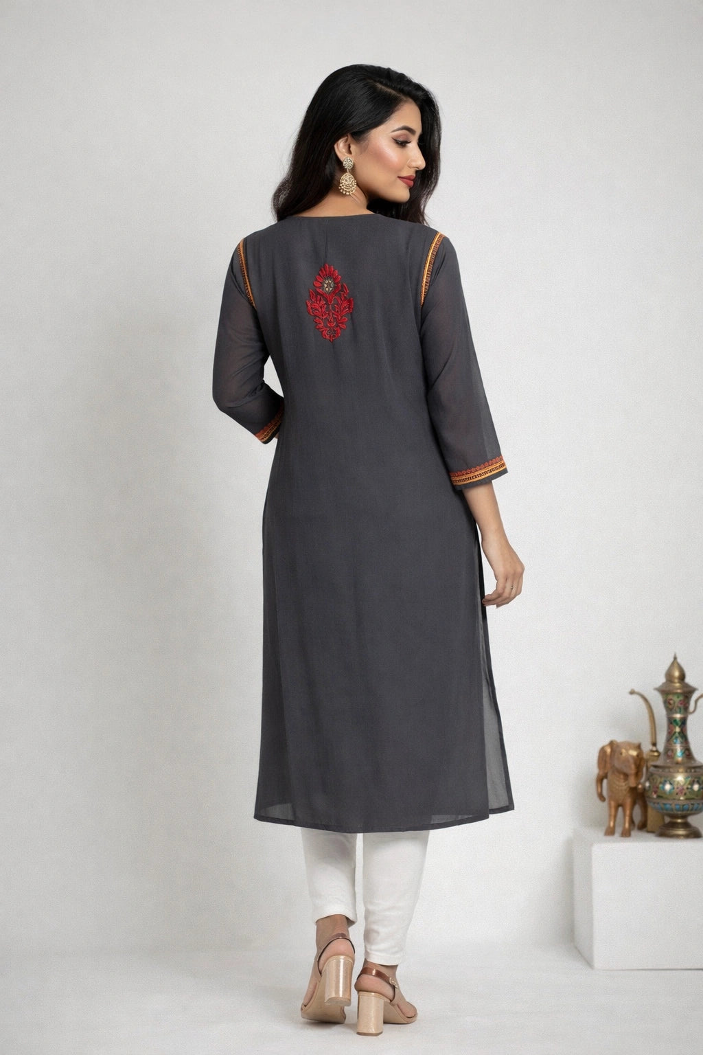 Woman wearing a lucknowi chikankari dark gray kurta with white pants on a light gray background