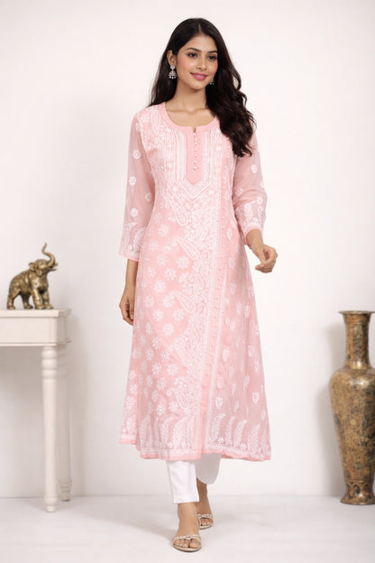 Woman wearing a peach embroidered kurta with white pants in a minimalistic setting.