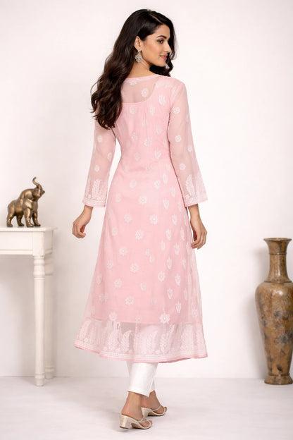 Woman wearing a chikan light peach kurta with white floral patterns in a minimalistic setting.