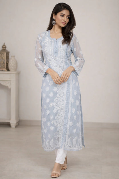 Woman wearing a light blue embroidered kurta with white pants in a minimalistic setting.