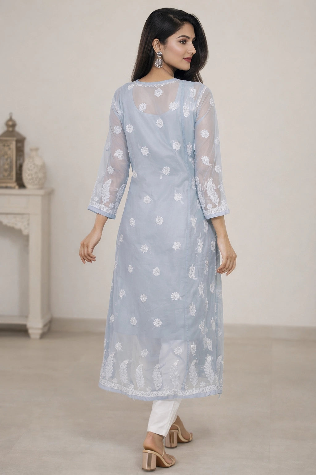 Woman wearing a chikan light blue kurta with white floral patterns in a minimalistic setting.