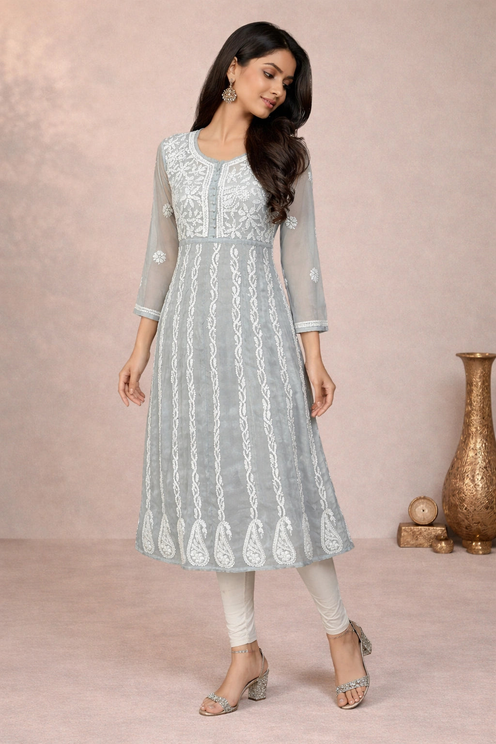 Woman wearing a light gray embroidered kurta with white pants against a pink background