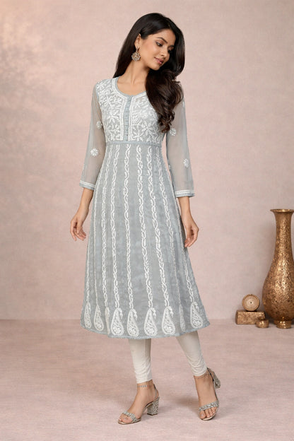 Woman wearing a light gray embroidered kurta with white pants against a pink background
