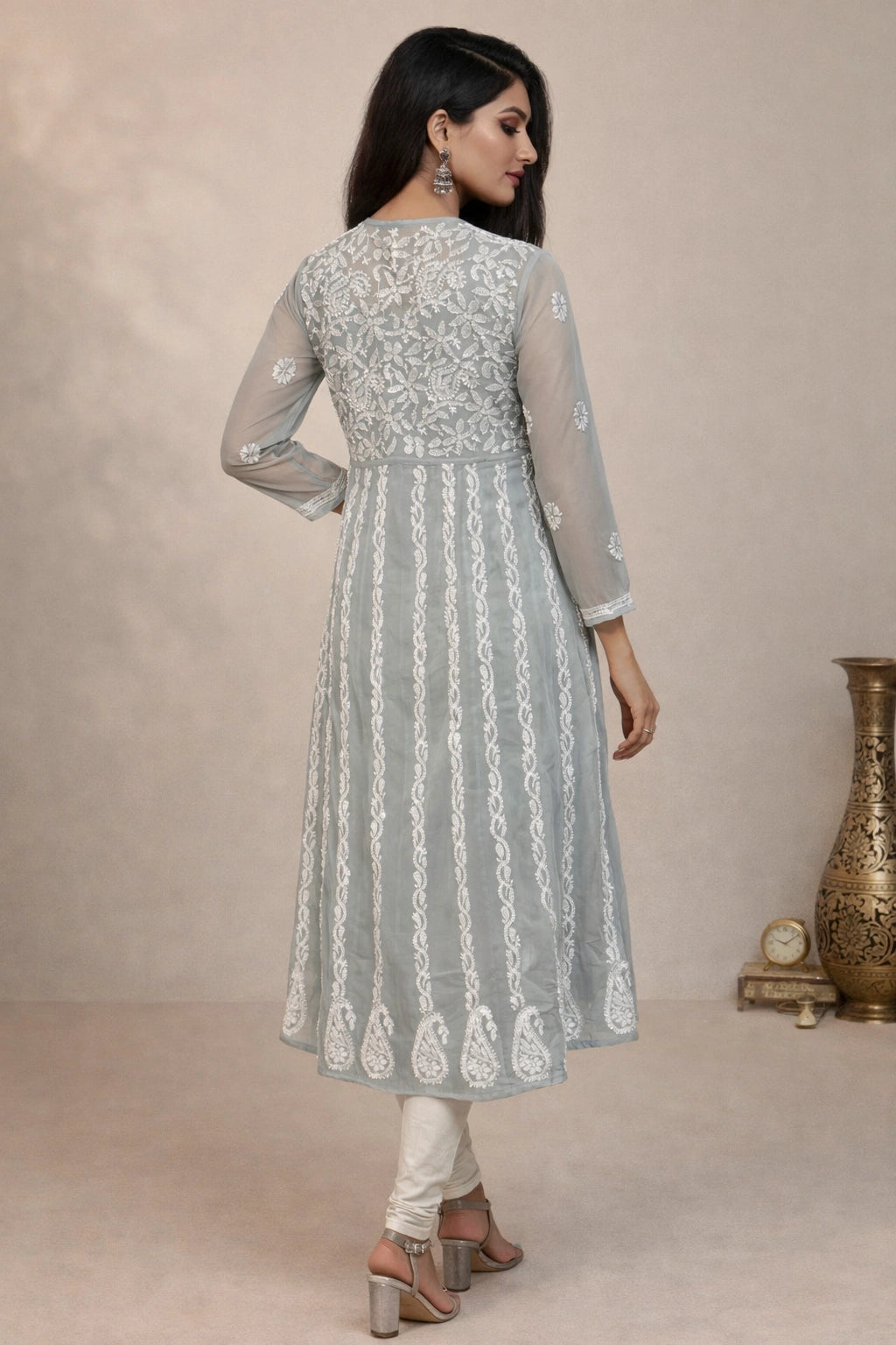 Woman wearing a light gray embroidered kurta with white pants against a beige background