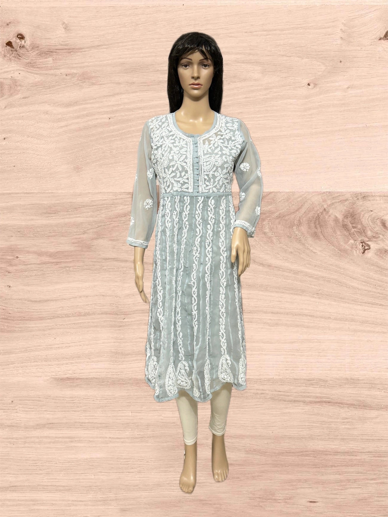 Light blue embroidered dress on a mannequin against a wooden background