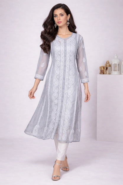 Woman wearing a embroidered light gray traditional outfit with white patterns on a white background