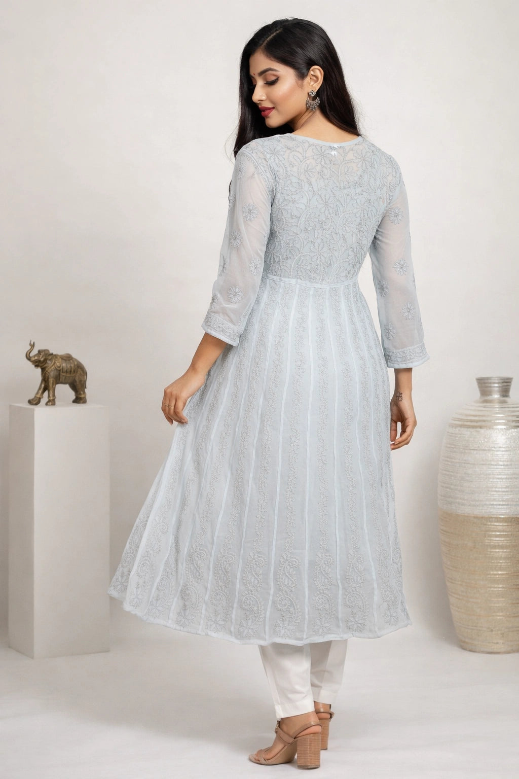 Woman wearing a lucknowi light blue kurta with white pants in a minimalistic setting.