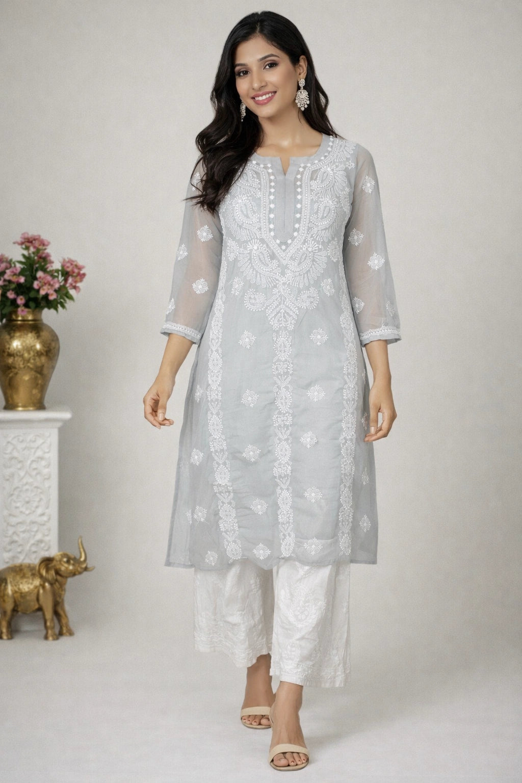 Woman wearing a light gray kurta with white floral patterns on a plain background