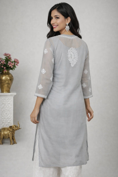 Woman wearing a gray kurta with white embroidery in a minimalistic setting.