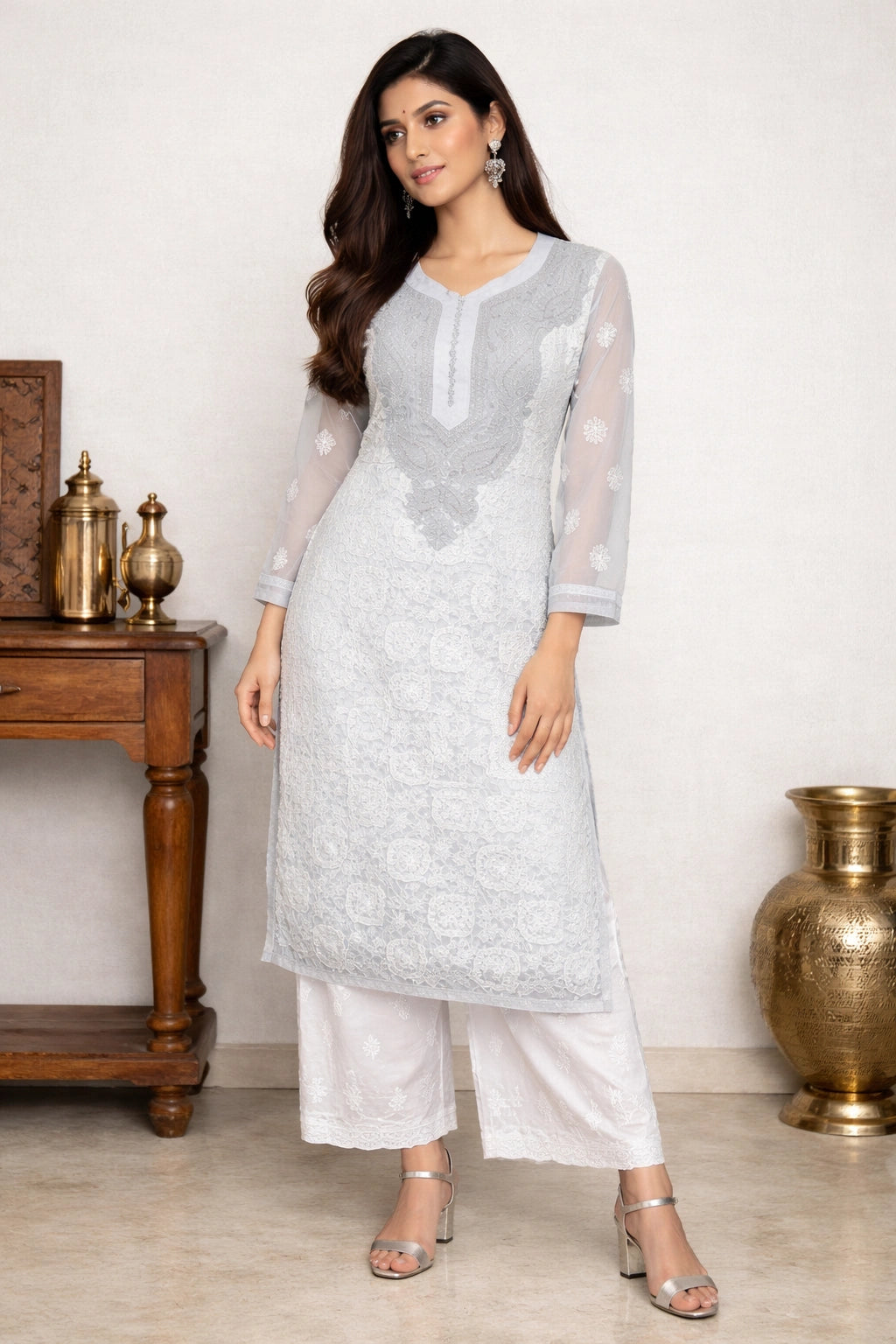 Woman wearing a lucknowi chikankari light gray kurta with white pants in a minimalistic setting.