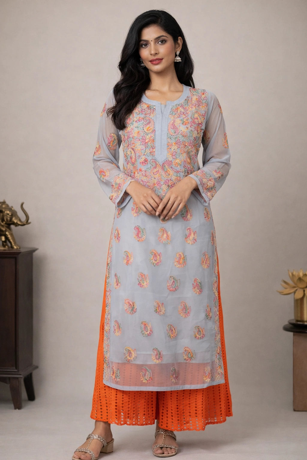 Woman wearing a light blue and orange traditional outfit with floral patterns on a neutral background