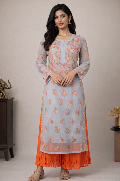 Woman wearing a light blue and orange traditional outfit with floral patterns on a neutral background