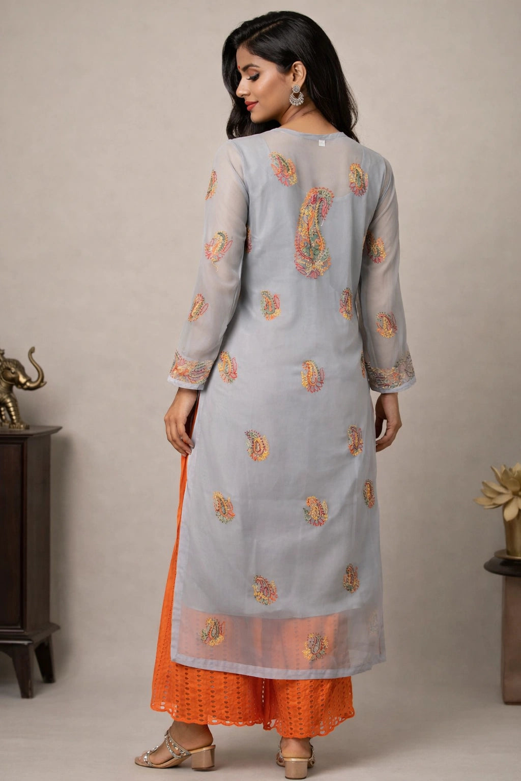 Woman wearing a light blue embroidered kurta with orange pants against a neutral background