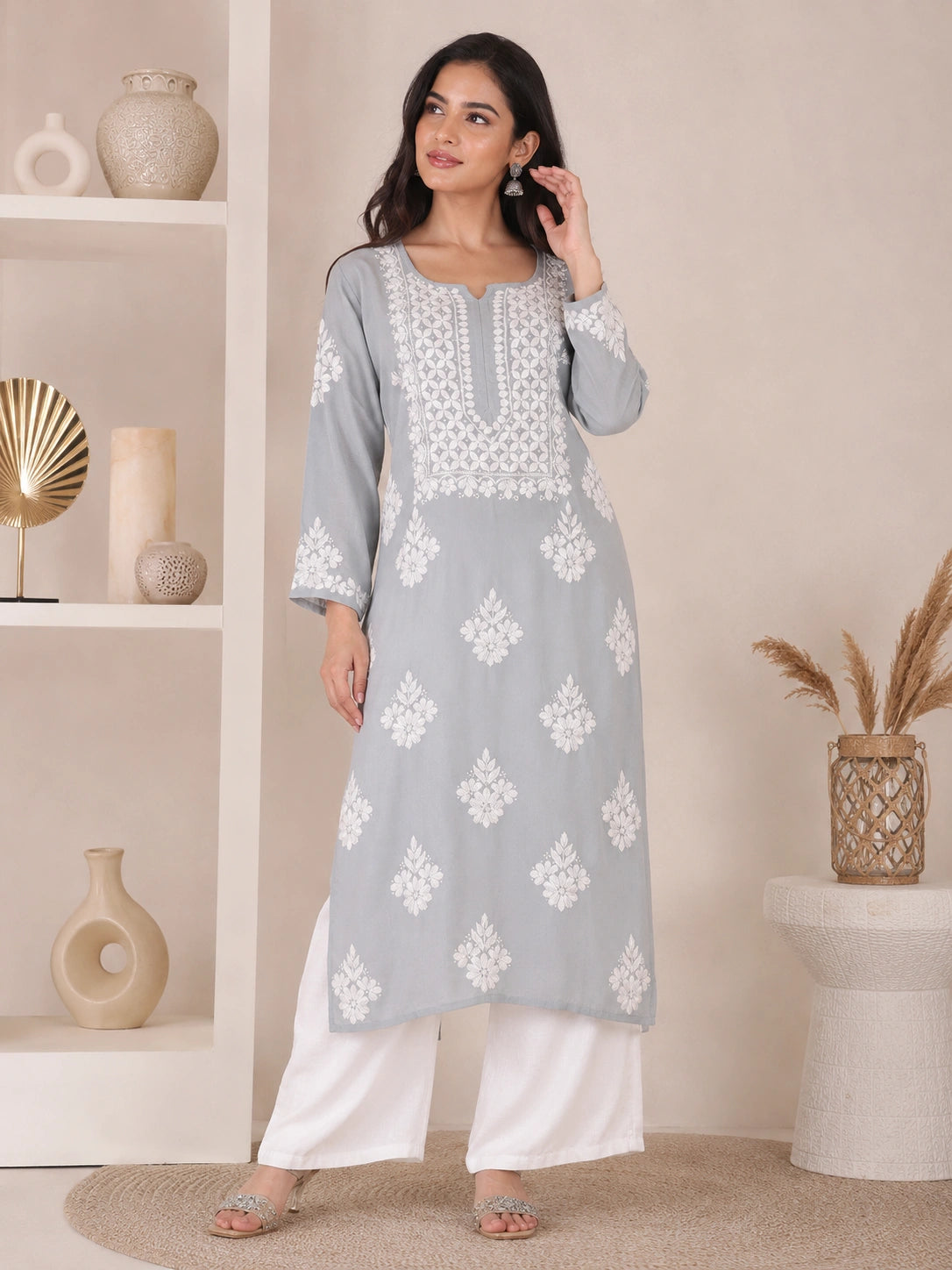 Woman wearing a grey embroidered kurta with white patterns on a beige background