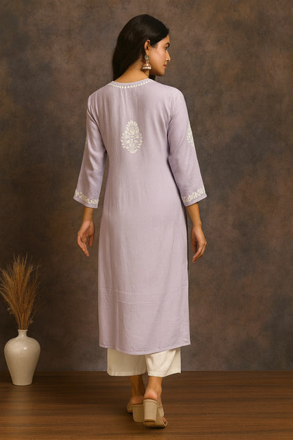 Woman wearing a light purple kurta with white embroidery against a brown background